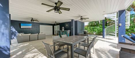 An outdoor patio with a dining table, chairs, and ceiling fans.