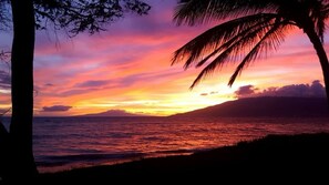 A sunset over a beach with palm trees and a mountain in the background. - RARE, GATED, PRIVATE BEACHFRONT HOME! PRIVATE POOL, 6 BEDS 6 BATHS (Kihei)