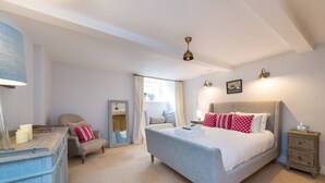 A bedroom with a large bed, bedside tables, a dresser, and a mirror.