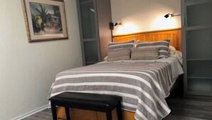 A bedroom with a bed, a bench, a framed picture, and a nightstand.