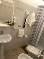 Uma casa de banho com lavatório, espelho, toalheiro, chuveiro e sanita.