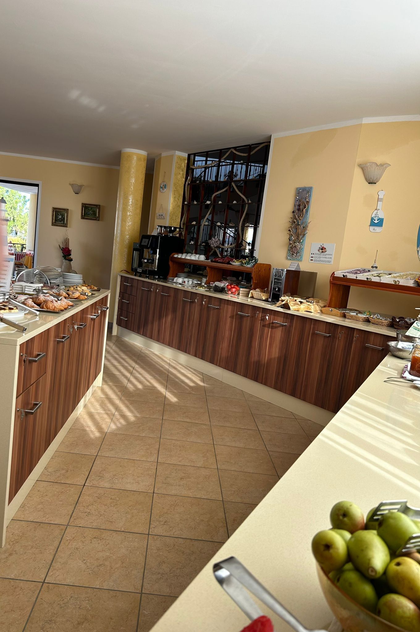 A breakfast bar with various food items, a coffee machine, and a fruit bowl.