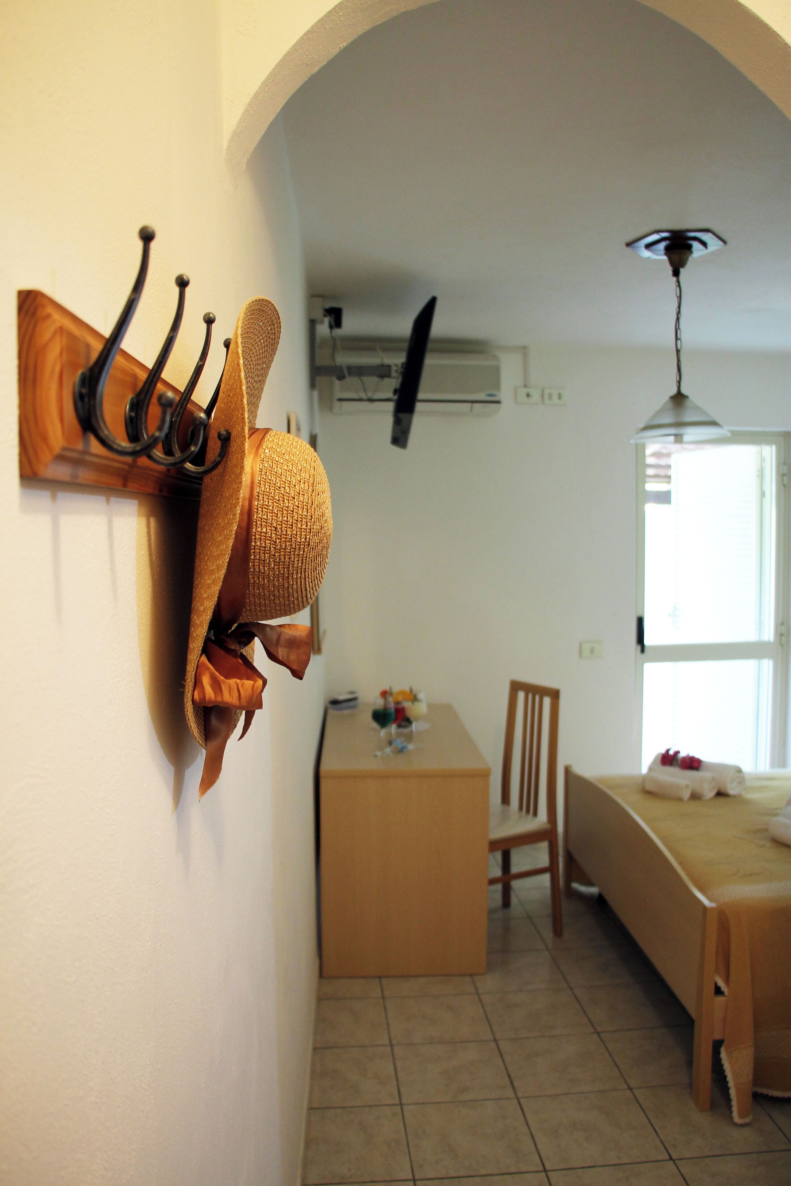 A room with a dining table, a chair, a bed, and a hat rack.