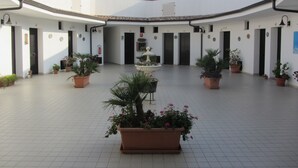 Un patio con varias puertas, plantas en macetas y suelo de baldosas.