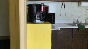 A kitchen with dark wooden cabinets, a yellow countertop, a coffee maker, and a red pot. - Comfortable 3 Bedroom Cabin On the Shores of Lake Chippewa Flowage in Hayward WI (Hayward)