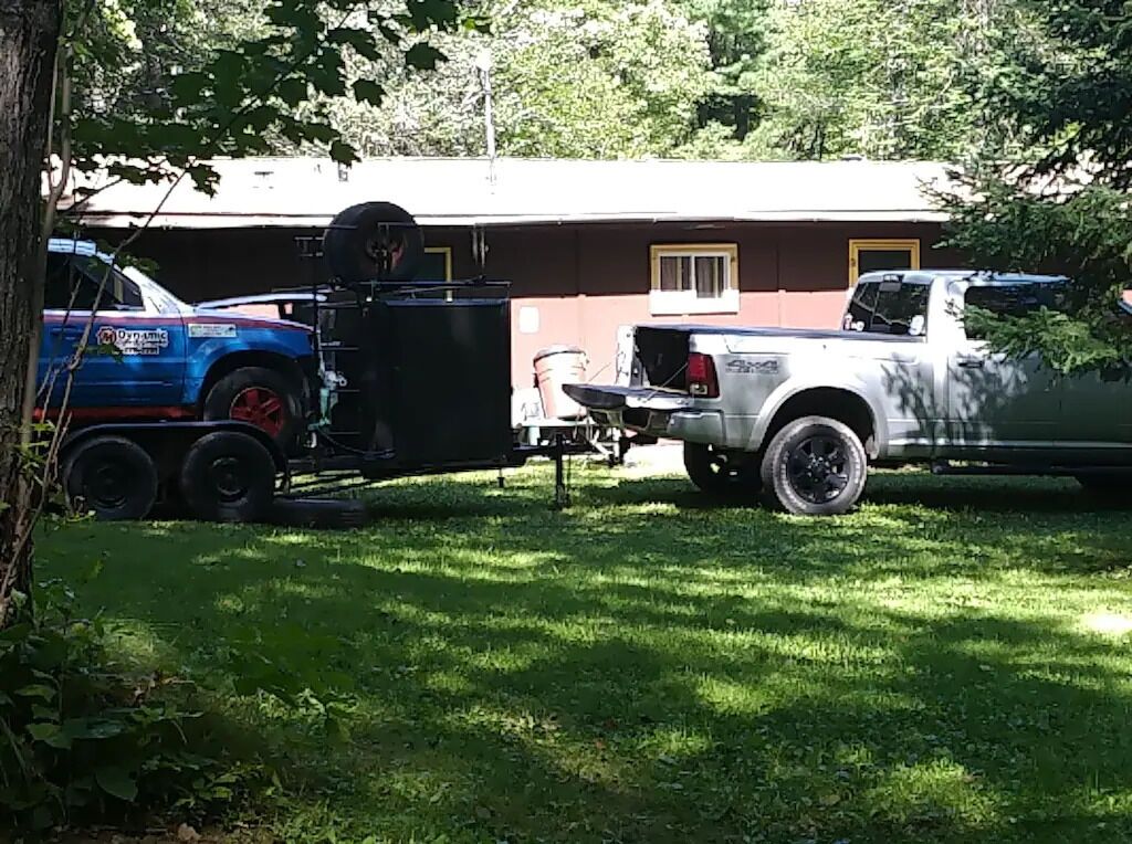 A truck with a trailer parked in a grassy area.