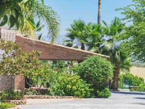 Escape to a serene garden oasis with a paved walkway, lush greenery, and a charming brick structure.