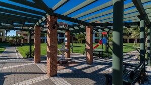 Un espacio al aire libre cubierto con pilares de ladrillo, una fuente y un área de juegos.