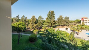 Vista de un jardín ajardinado con árboles y una zona de piscina.