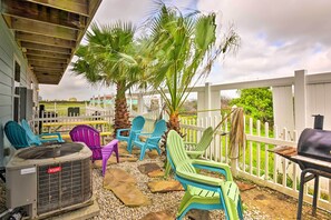 Relax in a serene outdoor space with Adirondack chairs, a grill, and a shaded area beneath a mature palm tree.