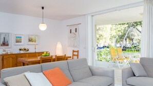Un soggiorno moderno con un divano grigio, un tavolo da pranzo con sedie e vista su un'area patio esterna.