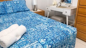 Een slaapkamer met een bed, een bureau, een spiegel en een nachtkastje.