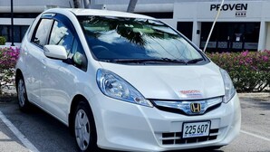 Een witte Honda auto geparkeerd op een parkeerplaats, met een gebouw van 'PROVEN BANK' op de achtergrond.