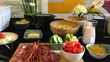 A kitchen counter with various food items including sliced meats, vegetables, and condiments.
