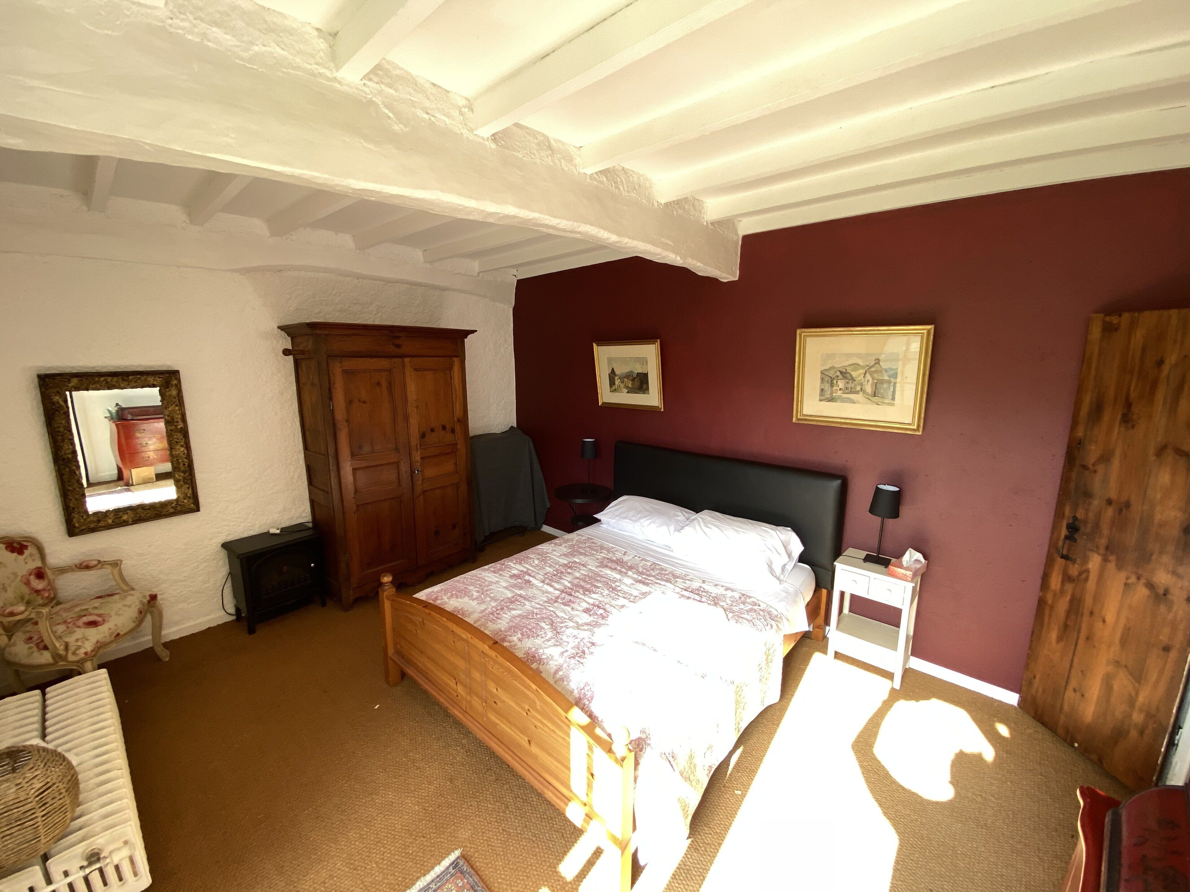 Un dormitorio con una cama de madera, un aparador, una silla y dos cuadros en la pared.