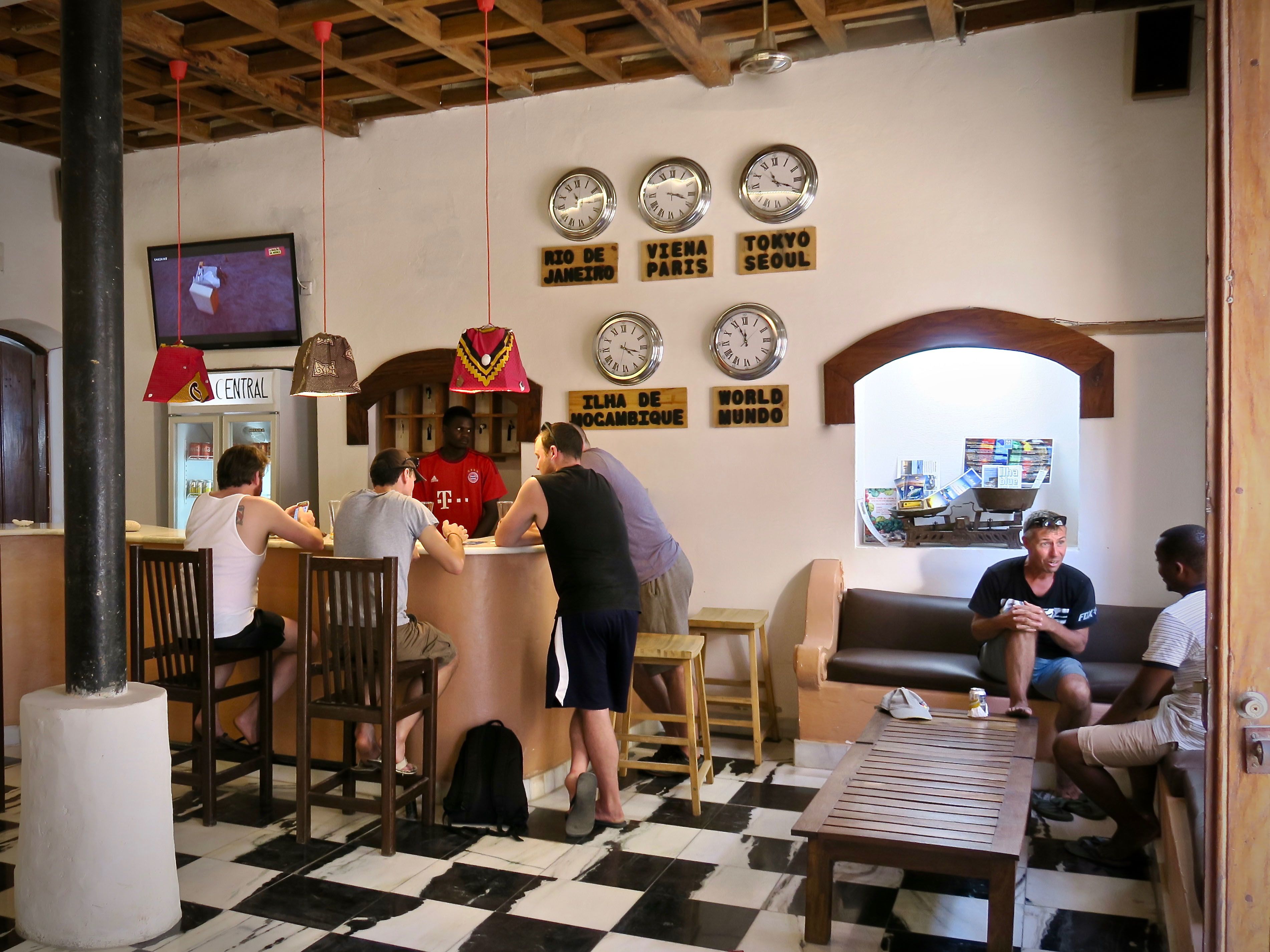 A bar area with wooden furniture, a central bar counter, and multiple clocks on the wall.