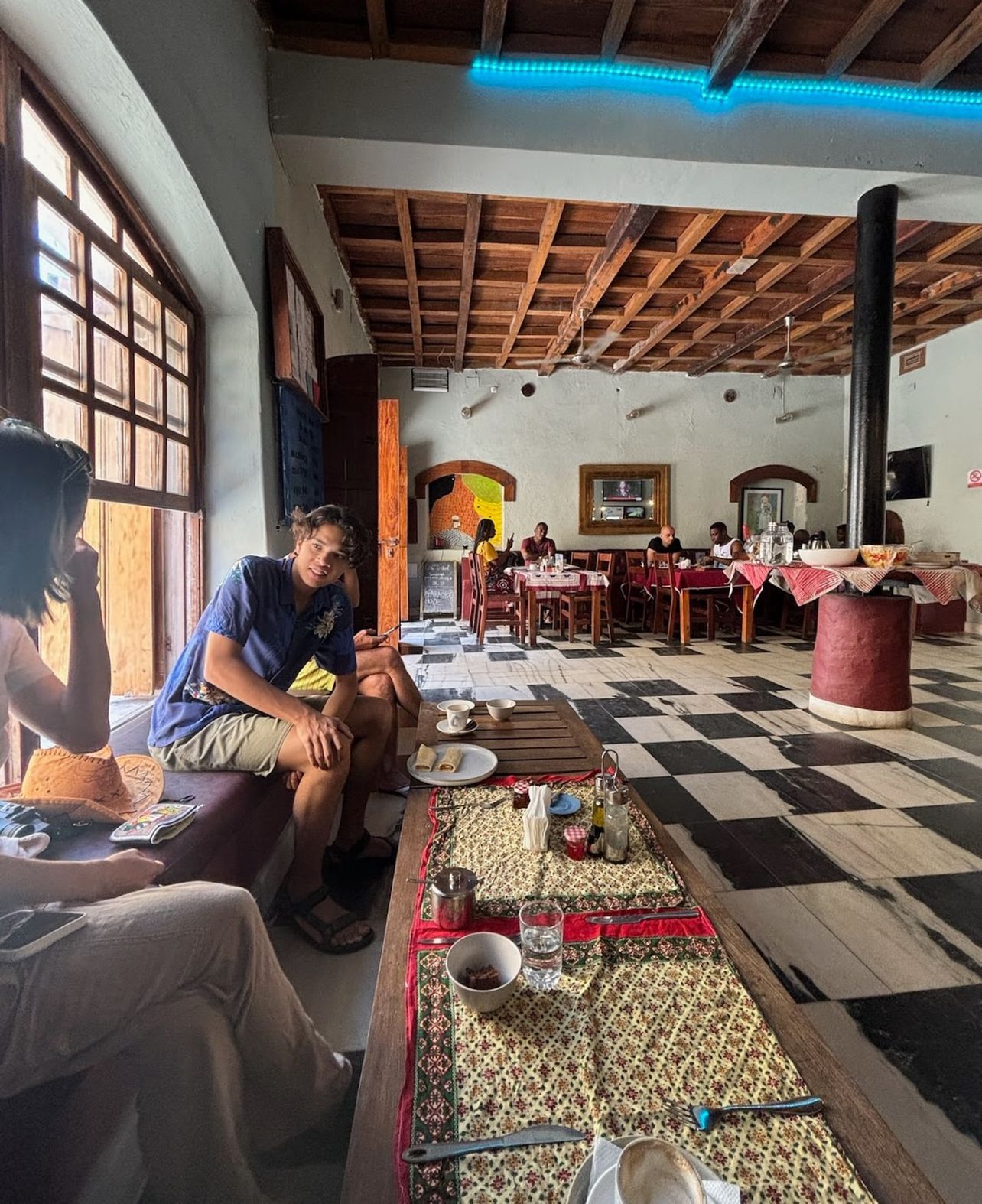 A dining area with checkered flooring, wooden tables, and chairs.