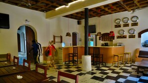 A restaurant with wooden tables and chairs, a checkered floor, and clocks on the wall. - Cafe Central (Mozambique Island)