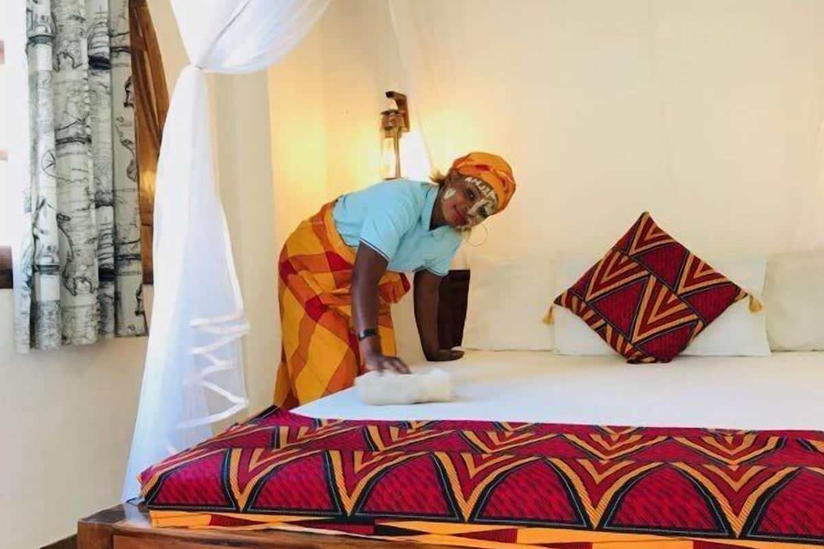 A bed with a patterned bedspread, a decorative pillow, and a canopy.