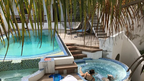 A pool area with a hot tub, wooden deck, and lounge chairs. - Cafe Central (Mozambique Island)