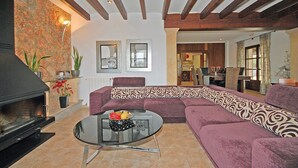 Una sala de estar con chimenea, un sofá, una mesa de centro y un comedor al fondo.