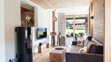 A modern living room with a flat-screen TV, a fireplace, a sofa, and a view of the outdoors.