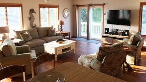A living room with a sofa, chairs, a coffee table, a TV, and a ceiling fan. - Beach House Rental Duck, NC (Duck)