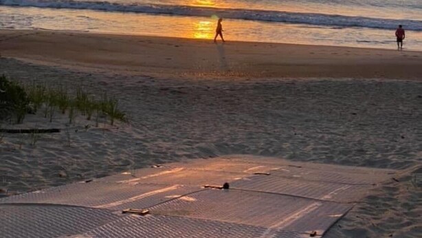 A beach at sunset with a person walking on the sand and another person standing in the water. - Beach House Rental Duck, NC (Duck)