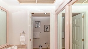Un baño con lavamanos de mármol, toallero, inodoro y fotografías enmarcadas en la pared.