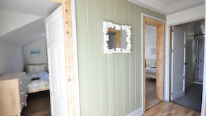 A room with a bed, a wooden dresser, a mirror, and a shower area.