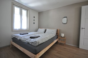 A single bed with a wooden frame, a bedside table with a lamp, a mirror on the wall, and a window with curtains. - Jungfrau Family Holiday Home, 5 bedrooms, sleeps 10, garden, BBQ, and parking (Matten bei Interlaken)