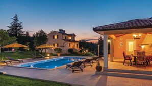 A poolside area with a swimming pool, lounge chairs, and a covered patio with outdoor furniture. - Amazing home in Labin (Labin)