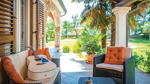 A covered patio with wicker furniture, a guitar, and a coffee table. - Amazing home in Labin (Labin)