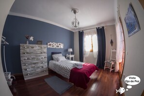 Un dormitorio con cama, cómoda, mesita de noche, silla y ventana con cortinas.