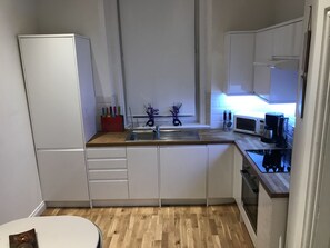 Compact kitchen with central island, sink, microwave, and coffee maker, plus ample storage and a small table.