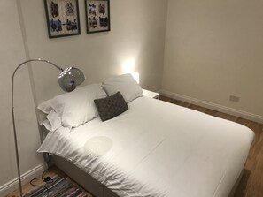 Restful retreat with a large bed, floor lamp, and framed artwork.