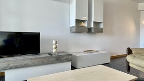 A modern living room with a flat-screen TV, a sculpture, and a small insect model on a white console table.