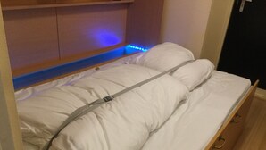 Een bed met witte beddengoed en een hoofdbord met blauwe LED-verlichting.