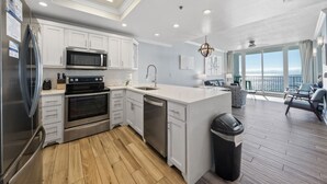 A modern kitchen with white cabinetry, stainless steel appliances, and a large island. - Lighthouse 714 (Gulf Shores)
