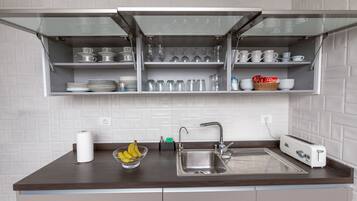 Una cocina con una estantería empotrada, un lavamanos, un tostador y un bol de plátanos.