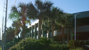 A parking garage with multiple levels, surrounded by palm trees and greenery.