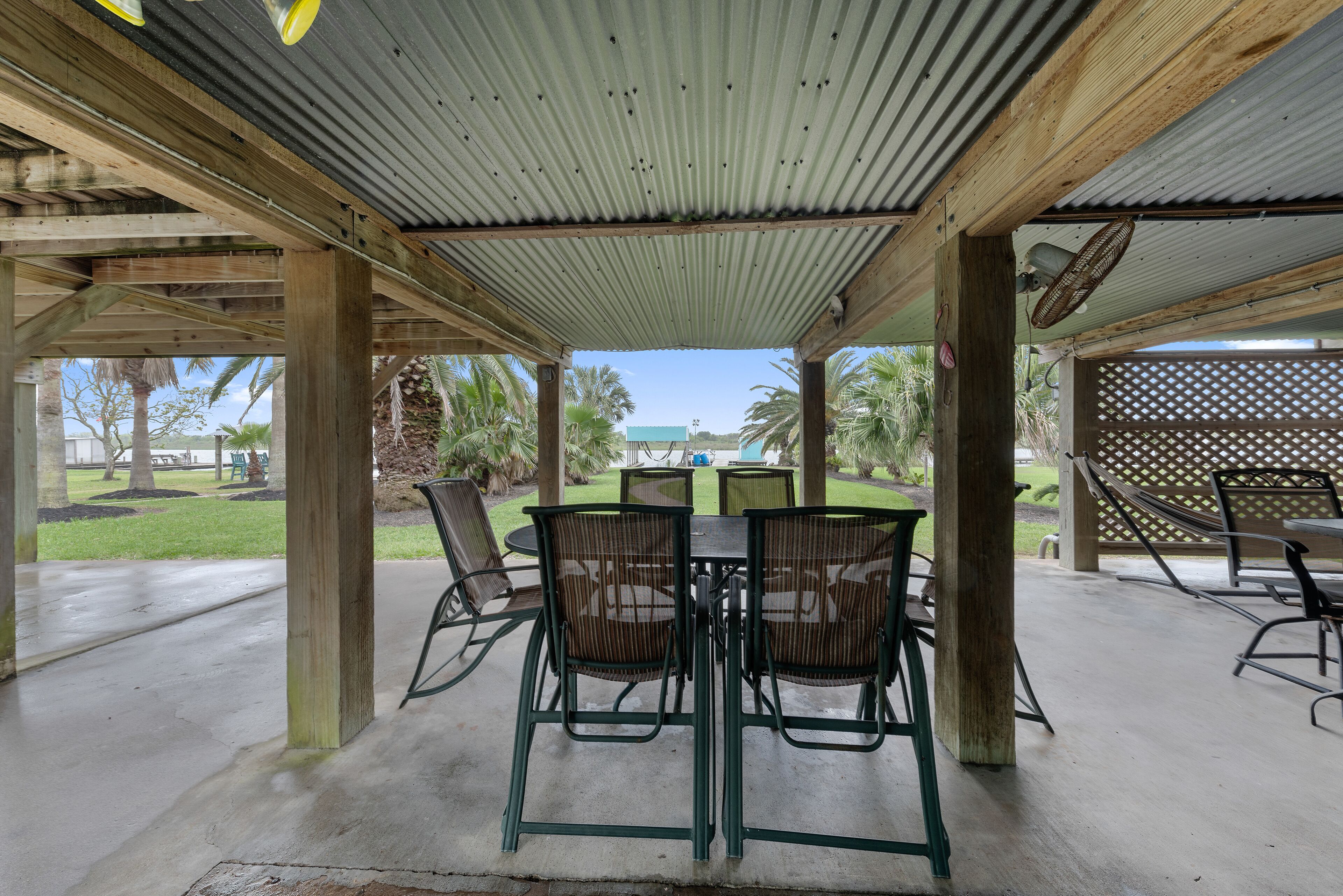 An outdoor patio with a covered seating area, a table, and chairs.