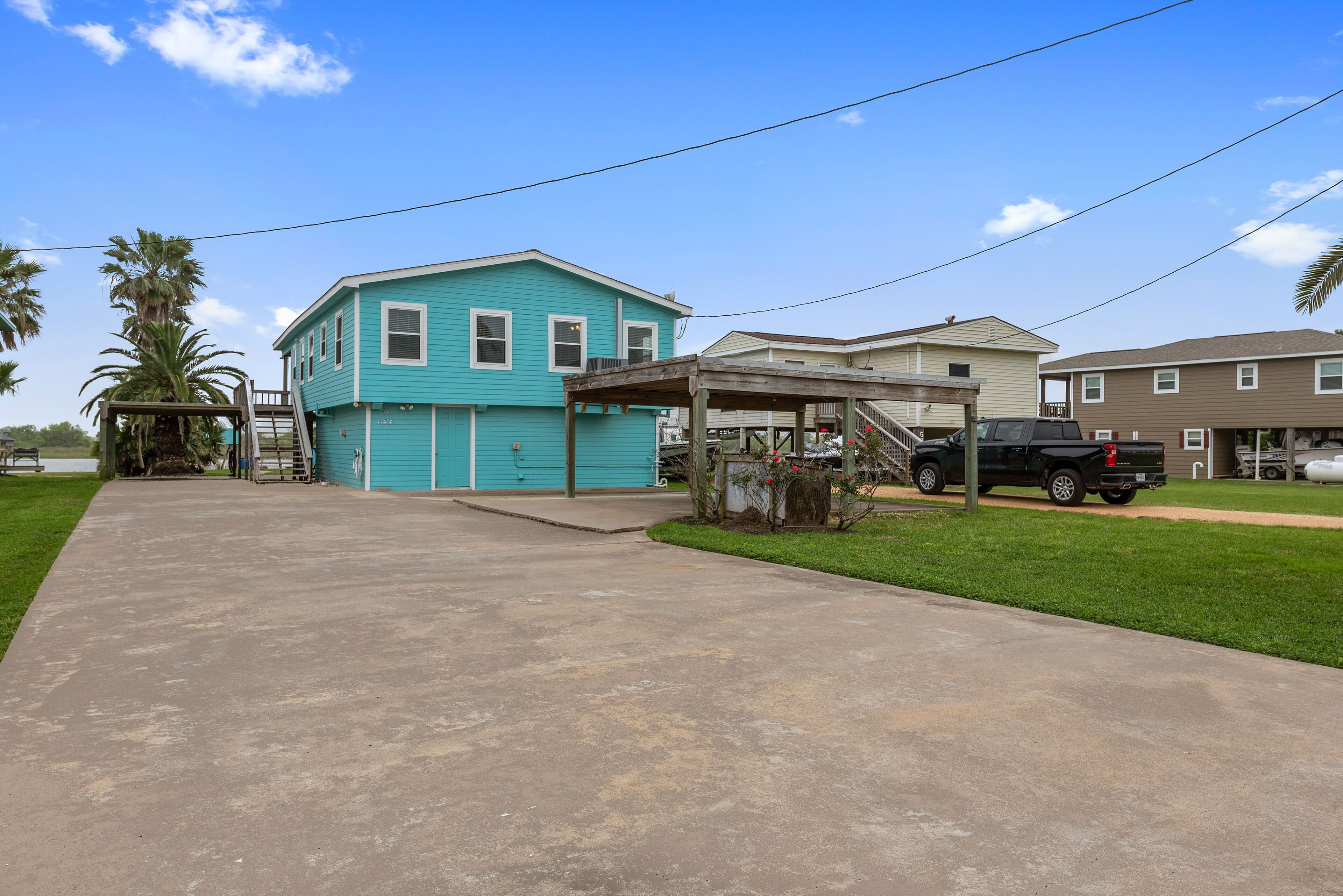 A residential area with a turquoise house, a covered porch, and a black truck parked nearby.