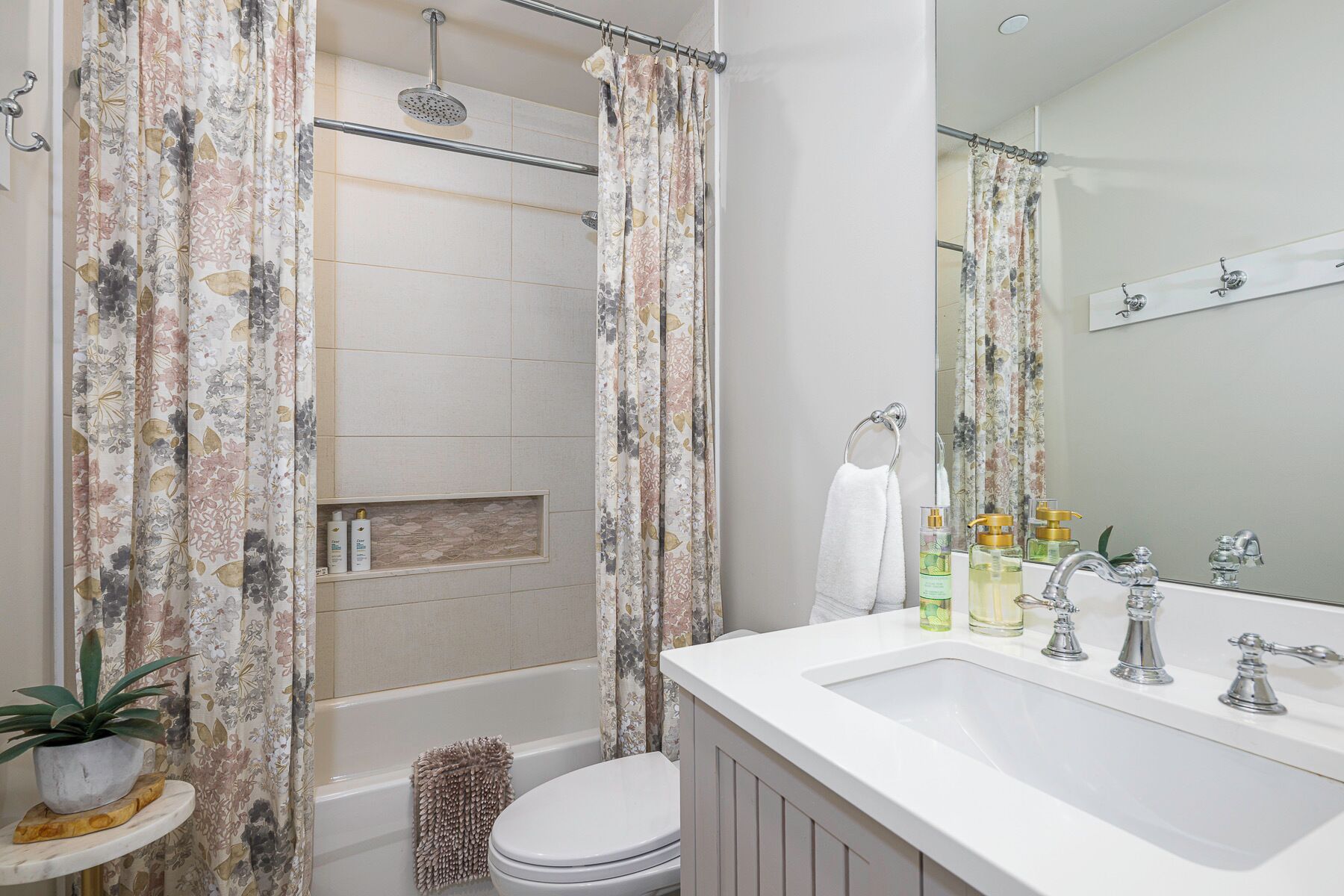 A bathroom with a shower, toilet, sink, and a mirror.