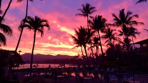Vista al atardecer con palmeras y una zona de piscina.