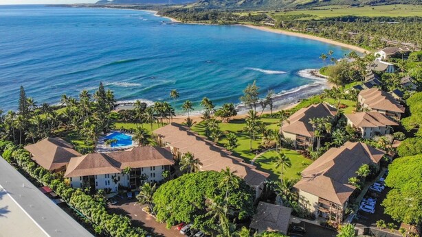 Un resort costero con varias edificaciones tipo bungalow, una playa y abundante vegetación.