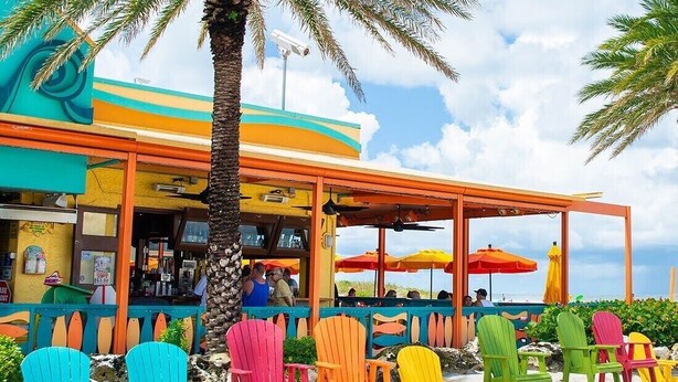 A beachside restaurant with colorful chairs and umbrellas. - "Private Pool Oasis • 3-Min
Walk to Crystal Beach •
Tropical Escape" (Crystal Beach)