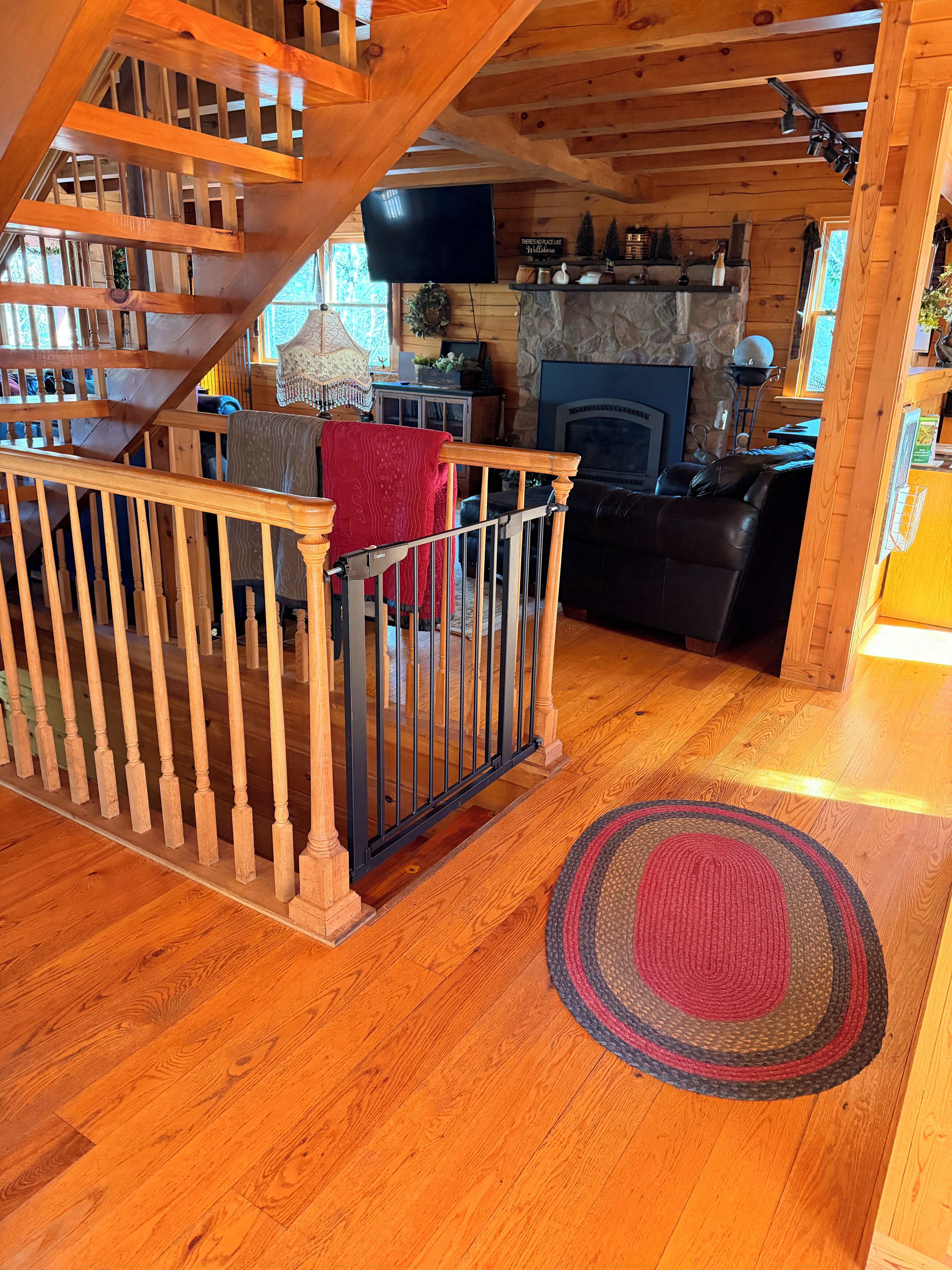 A wooden staircase leading to a living area with a fireplace, a television, and a cozy seating arrangement.