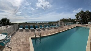 A pool area with lounge chairs and a view of the ocean. - Spacious, Luxury, Beach Condo with Pool (Indian Rocks Beach)