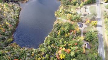 An aerial view of a lake surrounded by dense forest and a road.